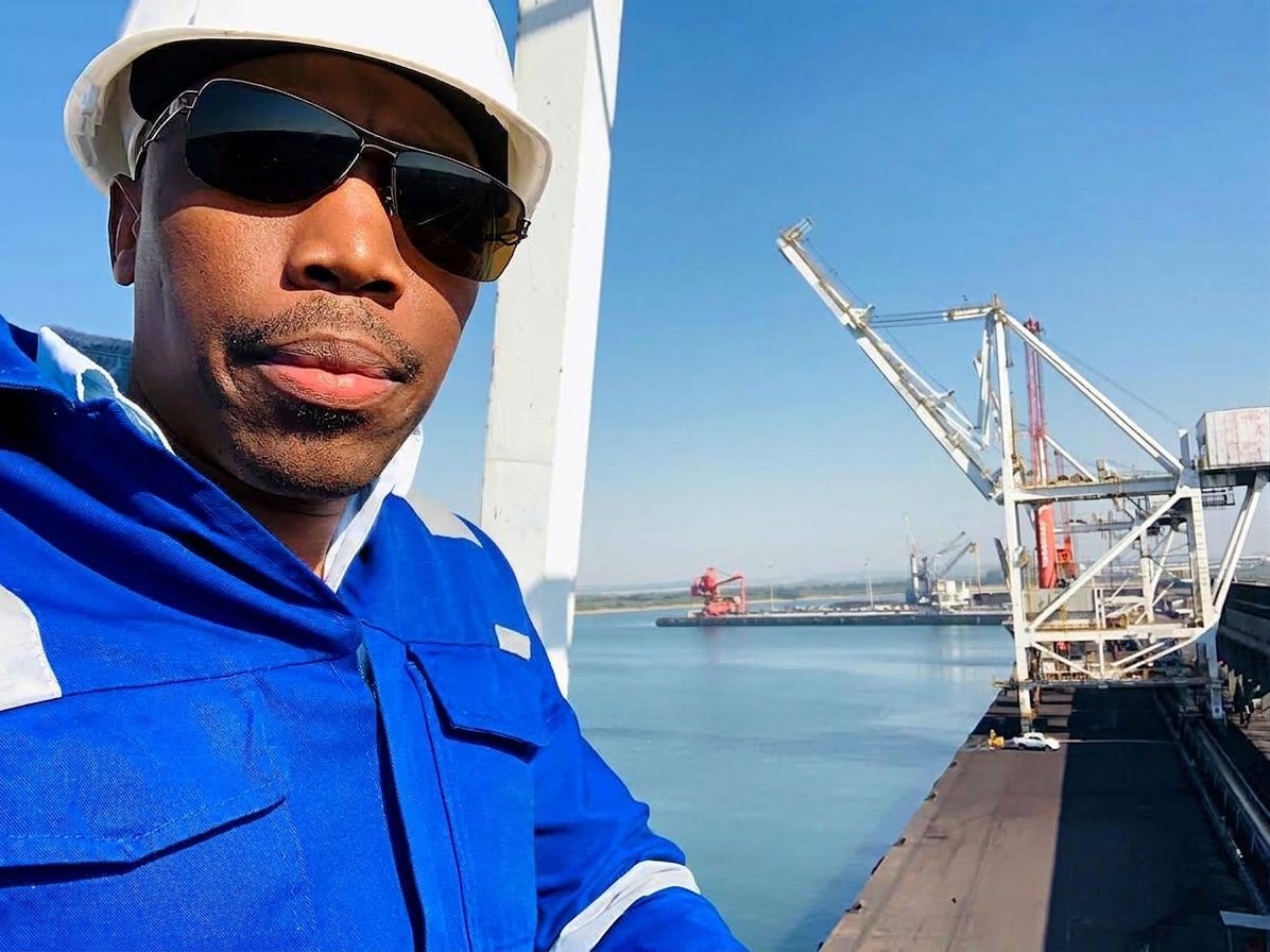 Engineer on site at a port terminal with ship loaders behind
